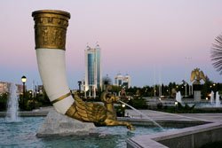 Modern city life in Ashgabat with a fountain and statue